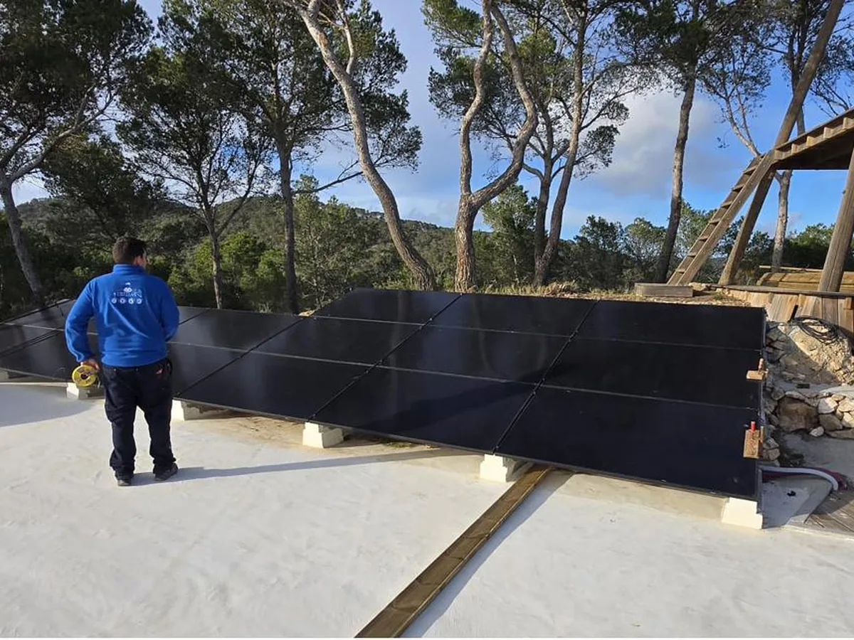 Gran instalación fotovoltaica con técnico revisando paneles solares
